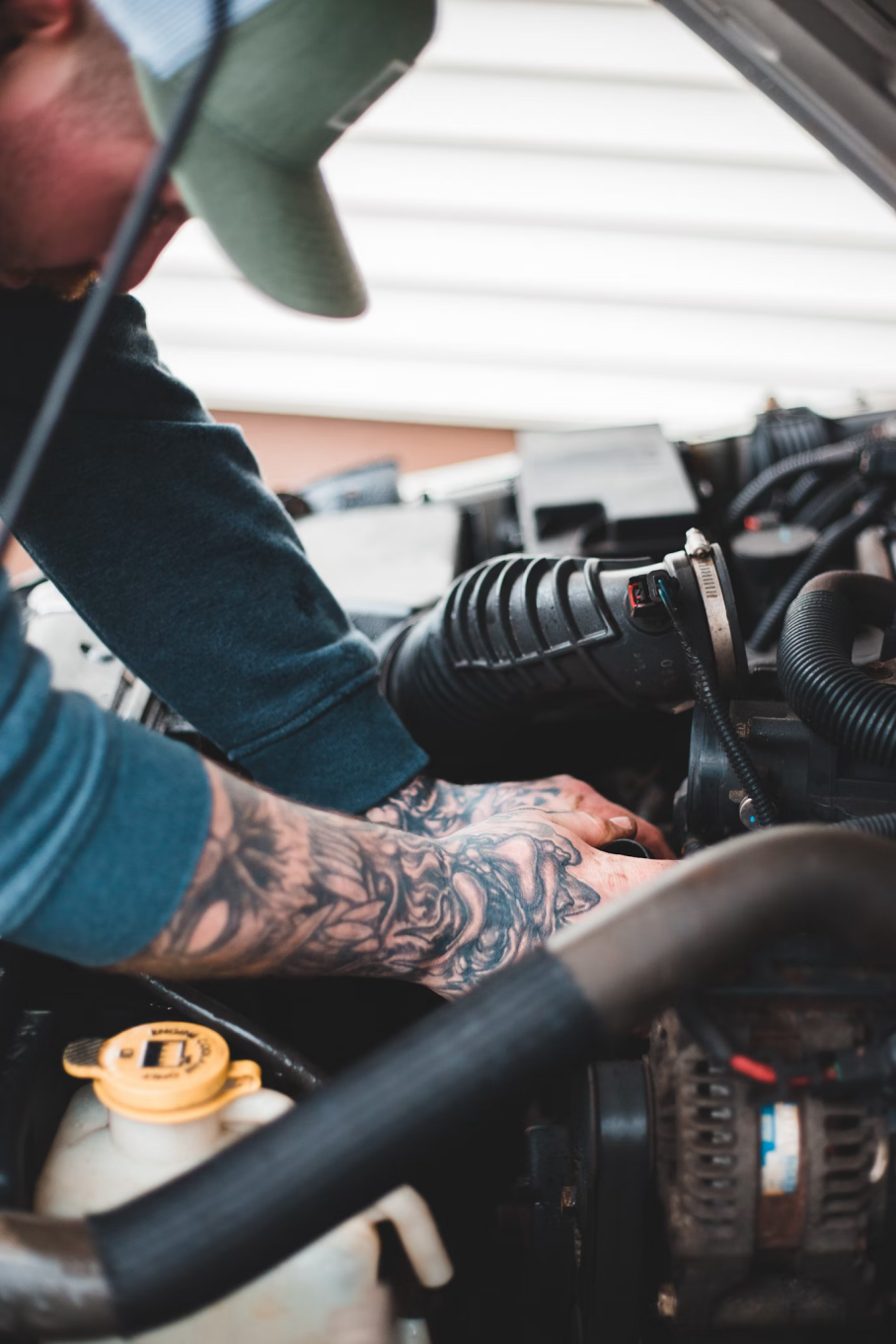 A mechanic inspecting a car’s air filter under the hood, checking for dirt and debris.