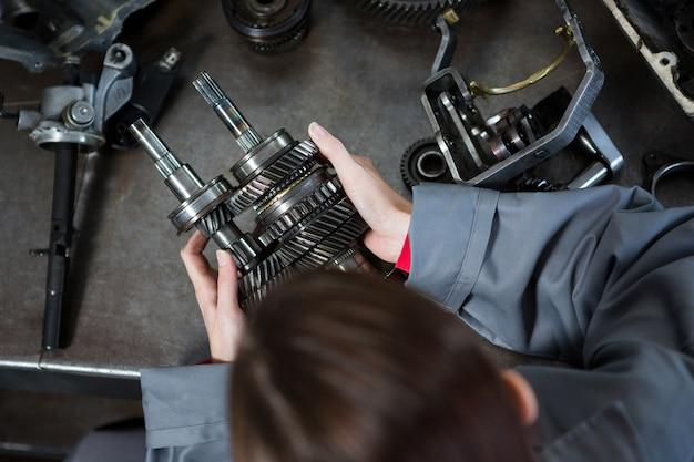 Female mechanic holding car transmission parts.