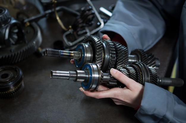 Female mechanic holding transmission parts for auto maintenance.